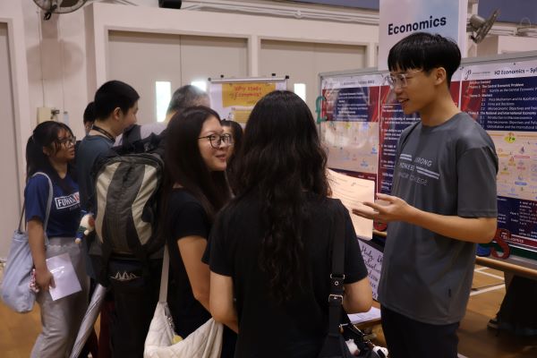 Students engaging visitors at the Economics booth